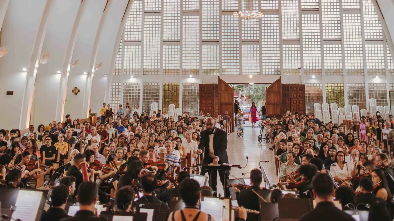 Orquestra em concerto sob a regência do maestro, diante do público